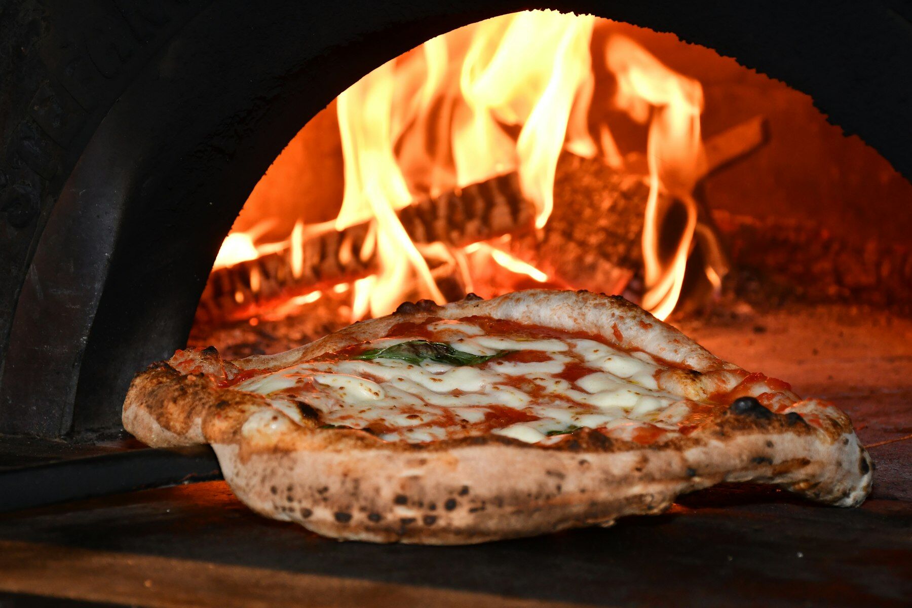 Pizza Margherita im Holzofen, Flammen im Hintergrund
